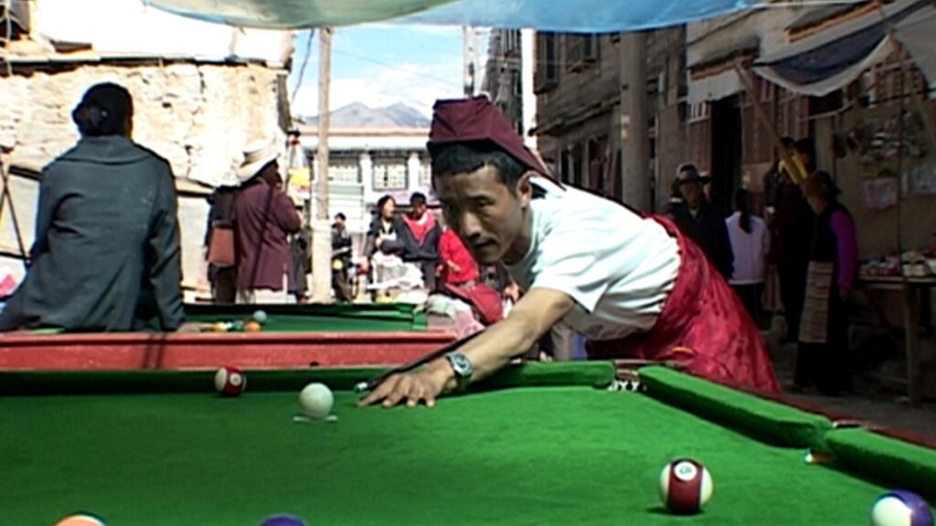 Ein Mönch spielt Billard auf einer Strasse in Tibet.