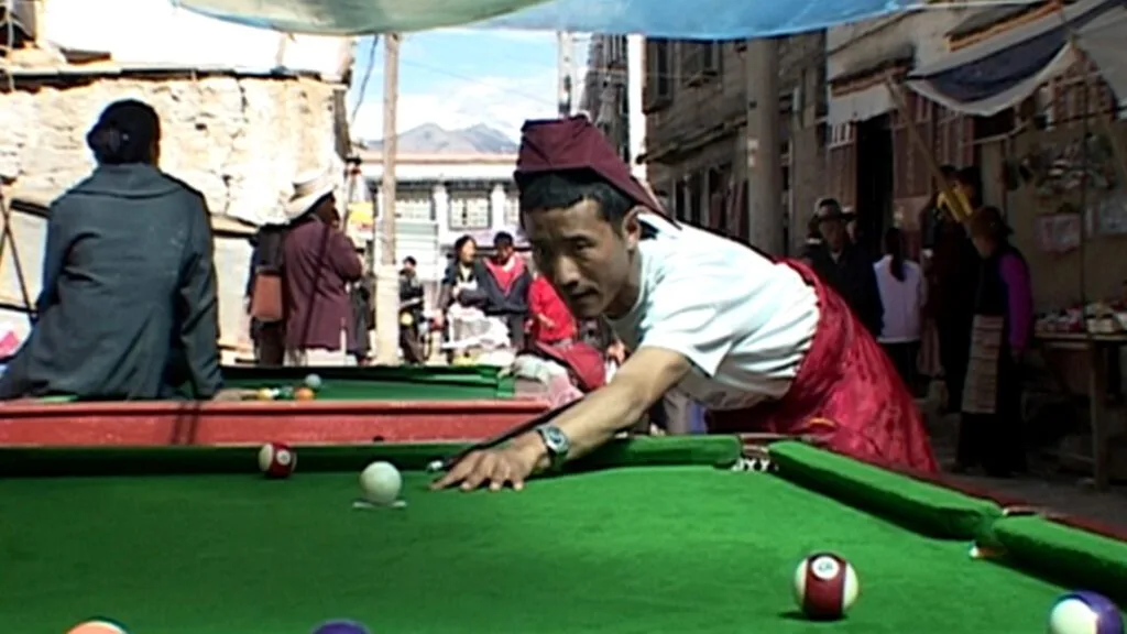 Un moine joue au billard dans une rue au Tibet.