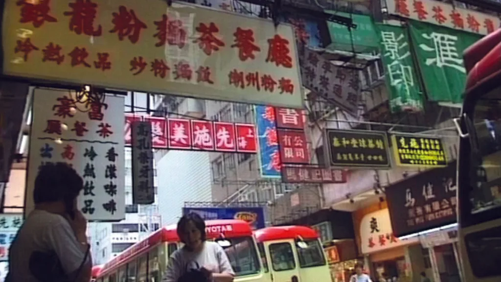 Belebte Strasse in Hongkong mit Leuchtreklamen und Minibus.