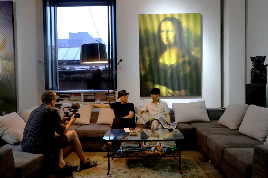 Filming in a modern living room with two interviewees on a sofa.